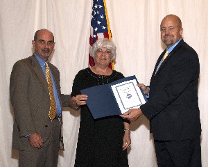Lynn Moad (c), Systems Integration Division chief, Headquarters Air Force Materiel Command (AFMC)/A-4, Wright-Patterson Air Force Base, Ohio, receives a gift of appreciation at the September luncheon from David Hart (r), chapter president, and Daniel Curtis, chapter vice president for programs.